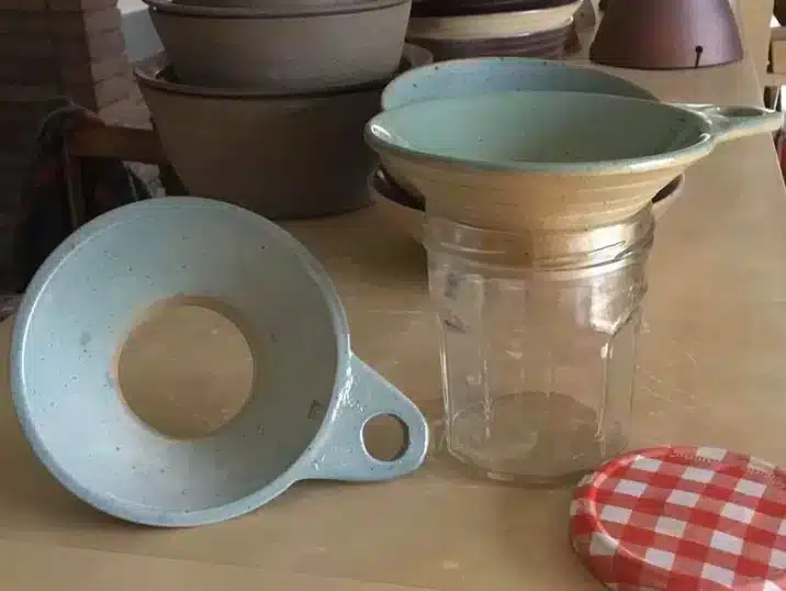 Twee confituur trechters gemaakt van klei bij een glazen bokaal en metalen deksel