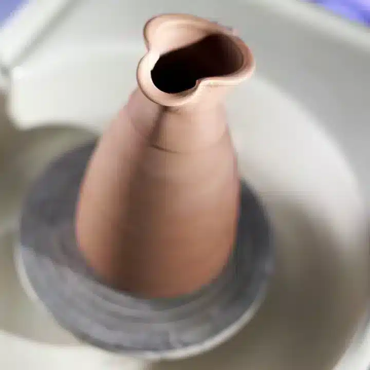 Een hoge kan gemaakt van rode klei op een draaischijf