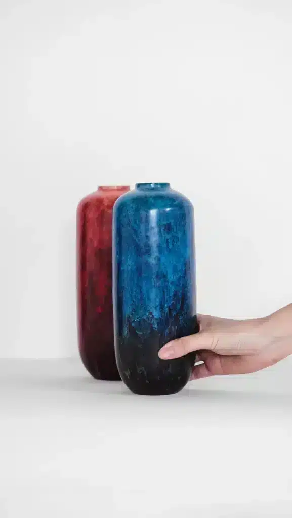 Een rode en blauw hoge smalle vaas van keramiek