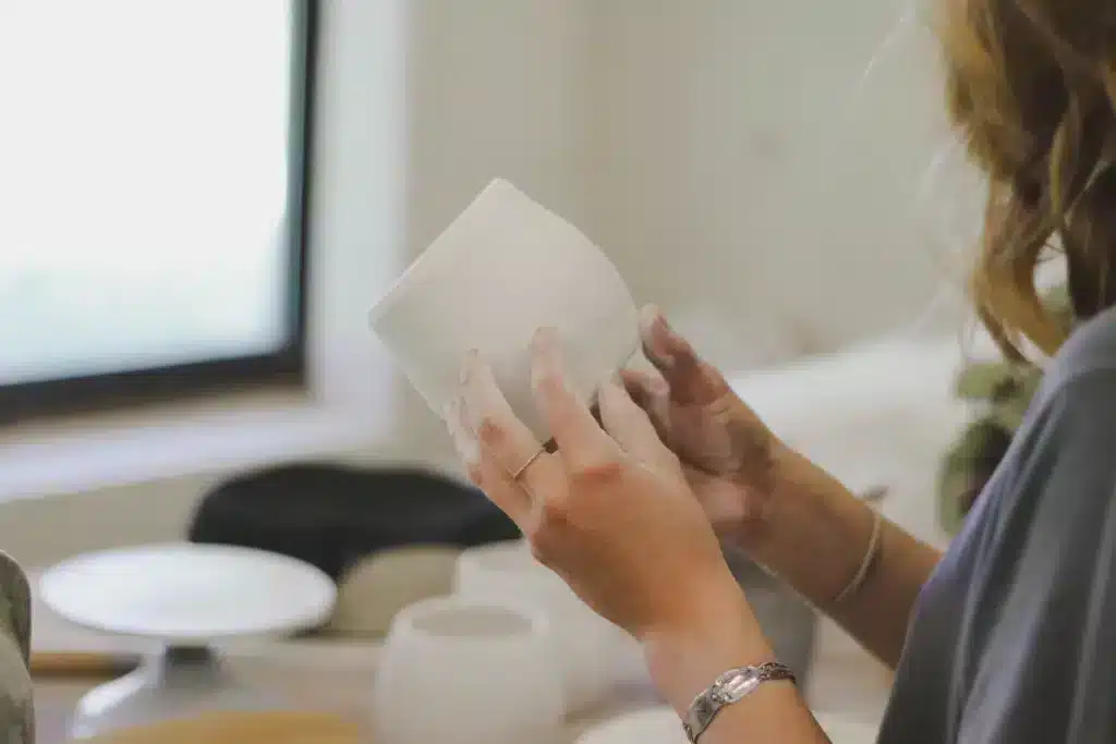 wanneer klei droog: twee handen met een pot gemaakt van witte klei