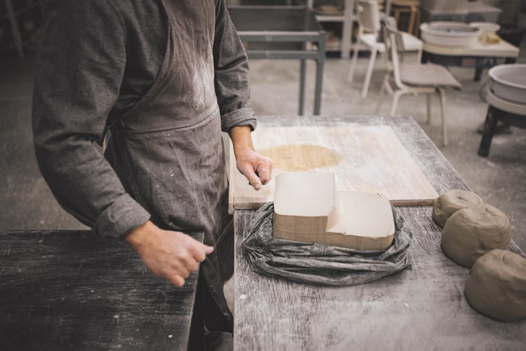 Welke klei voor keramiek: man staat in atelier voor een pak van klei