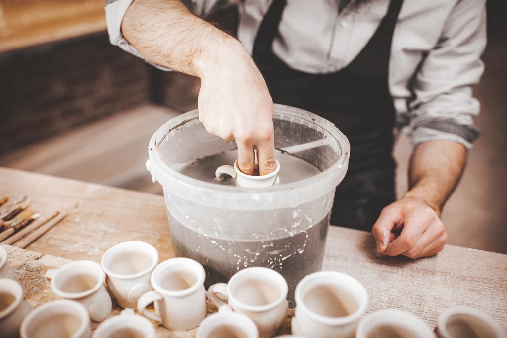 Een koffiekopje glazuren door het in glazuur te dompelen, keramiek vragen
