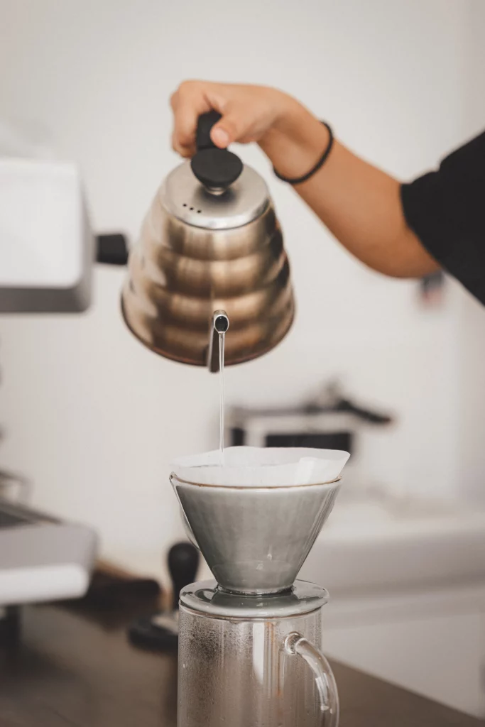 Vrouw giet water op voor koffie in een keramieken filter, keramiek vragen