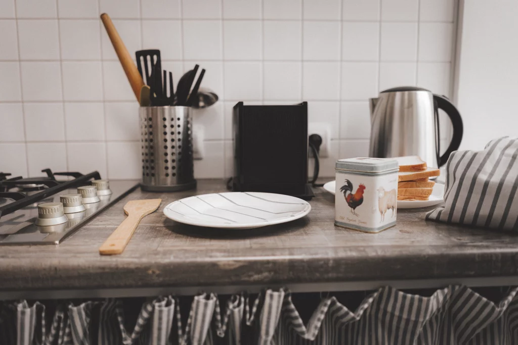 Aanrecht in de keuken met lepel en keramieken lepelbordje en potje met haan en schaap op