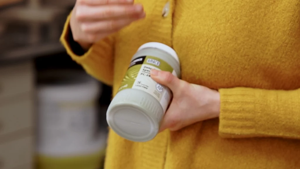 Glazuur voedselveilig maken: een keramiste houd een pot kant en klare glazuur in de hand