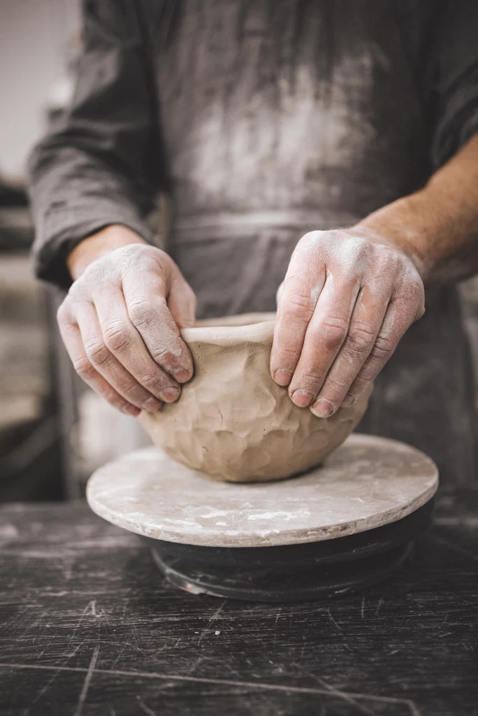 man vormt kom uit klei met handopbouw keramiek