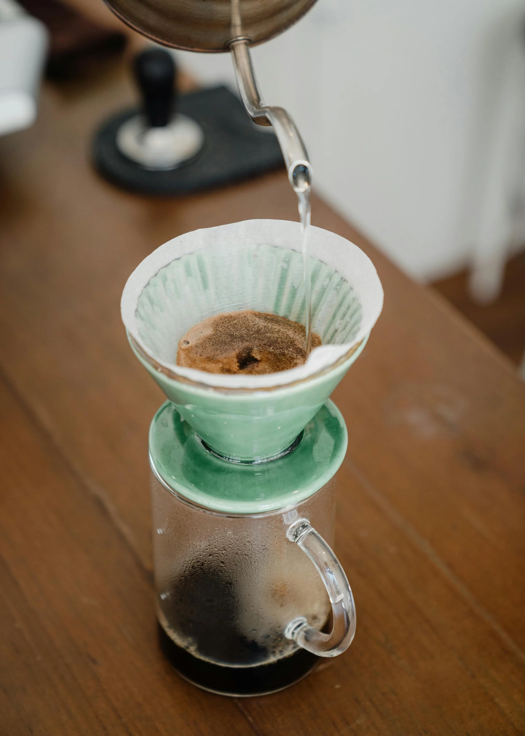 Keramiek maken keuken: er wordt koffie gegoten in groene keramieken koffiefilter